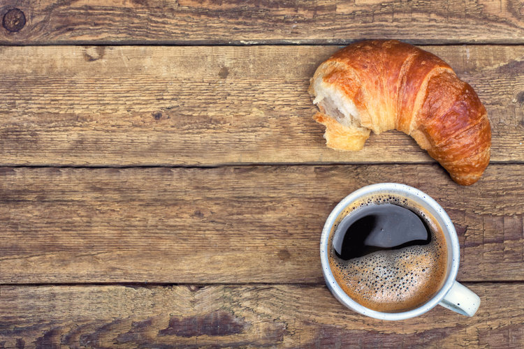 Coffee and croissant for breakfast on rustic wooden table, top view